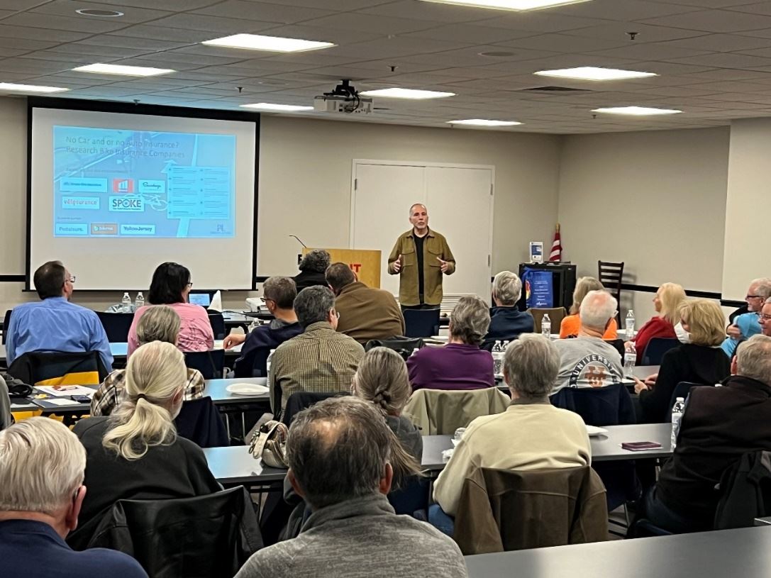 A person standing in front of a large room with a projector screen

Description automatically generated